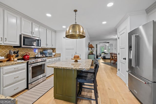 kitchen with appliances with stainless steel finishes, a sink, a kitchen breakfast bar, light stone countertops, and a center island