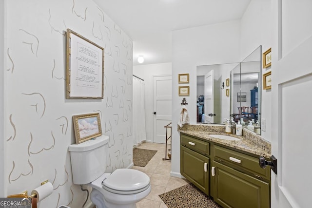 bathroom with toilet, vanity, baseboards, and tile patterned flooring