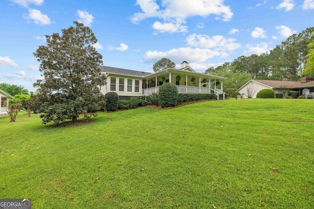 view of front of property featuring a chimney, covered porch, a detached garage, a front lawn, and an outbuilding