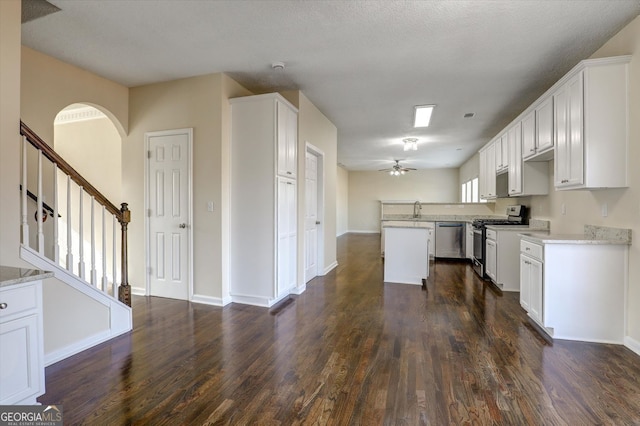 6793 Oconee Pl, Fairburn, GA 30213 - kitchen with appliances with stainless steel finishes, dark wood-type flooring, ceiling fan, arched walkways, and a kitchen island