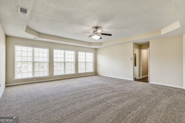 spare room with a tray ceiling, carpet, and a textured ceiling
