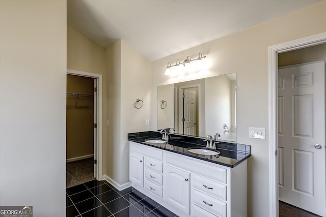 full bath featuring tile patterned floors, double vanity, a walk in closet, and a sink