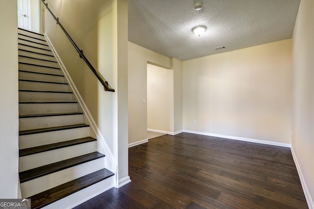 stairs with baseboards, visible vents, a textured ceiling, and wood finished floors
