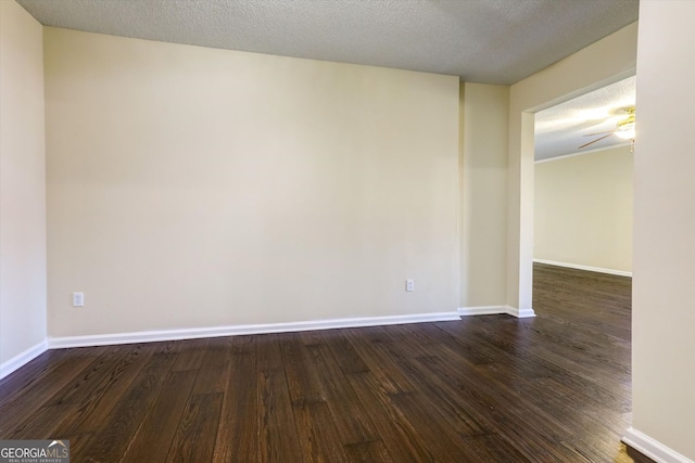 empty room featuring baseboards, dark wood-style flooring, and a textured ceiling