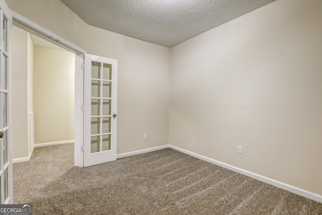 empty room featuring a textured ceiling, french doors, baseboards, and carpet floors
