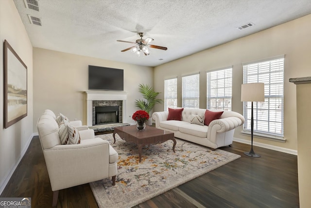 living area featuring a textured ceiling, visible vents, baseboards, and ceiling fan