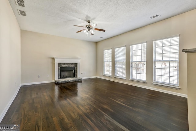 unfurnished living room featuring visible vents, dark wood finished floors, ceiling fan, baseboards, and a stone fireplace