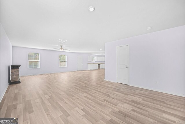 unfurnished living room featuring light wood-style flooring, baseboards, and a ceiling fan