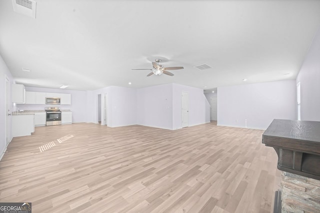 unfurnished living room featuring light wood-style floors, baseboards, visible vents, and ceiling fan