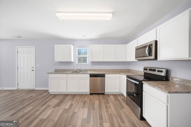 kitchen with light wood-style floors, white cabinetry, a sink, and appliances with stainless steel finishes