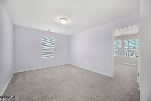 empty room with carpet, visible vents, and baseboards