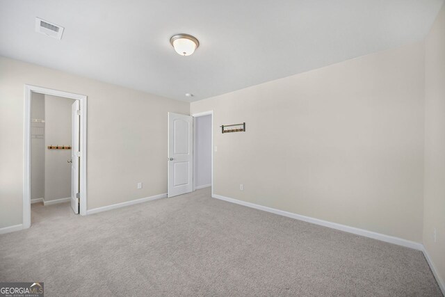 unfurnished bedroom featuring light carpet, baseboards, a spacious closet, and visible vents