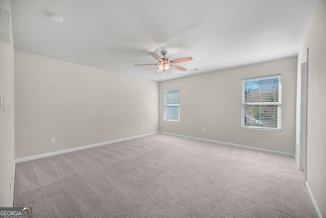 spare room with light colored carpet, baseboards, and a ceiling fan