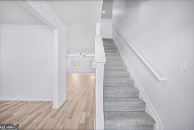 staircase with ceiling fan, baseboards, and wood finished floors