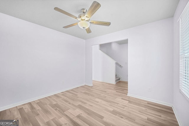 spare room featuring ceiling fan, light wood finished floors, and baseboards