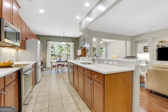 kitchen featuring open floor plan, recessed lighting, light countertops, a sink, and appliances with stainless steel finishes