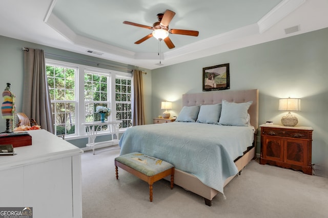 bedroom featuring a tray ceiling, light colored carpet, and visible vents