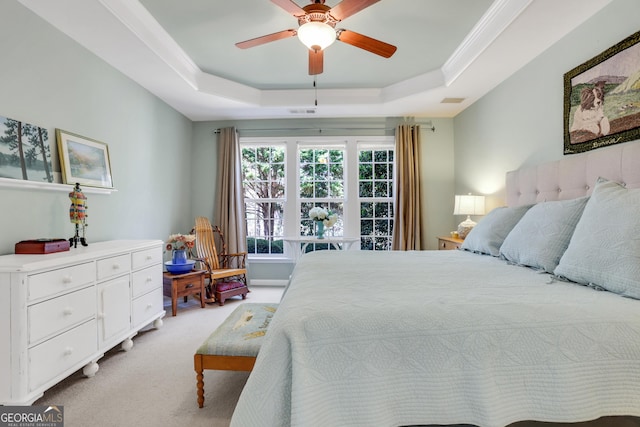 bedroom with crown molding, visible vents, light colored carpet, a tray ceiling, and a ceiling fan