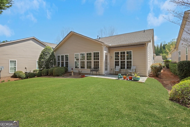rear view of house featuring a lawn, a shingled roof, and a patio area