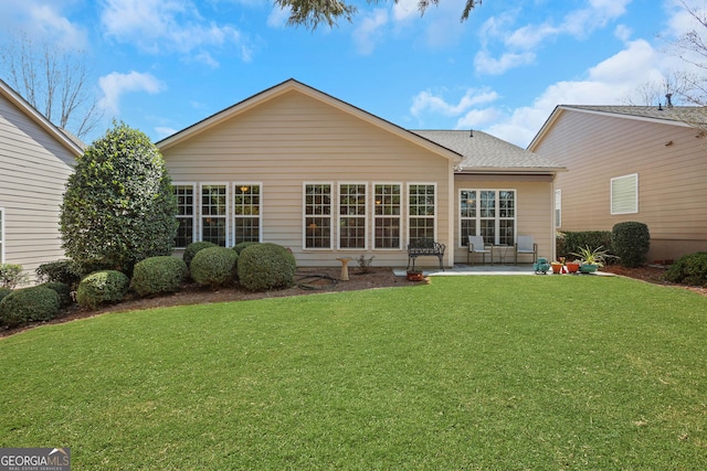 back of property featuring a patio, a shingled roof, and a lawn