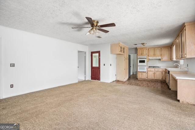 kitchen with under cabinet range hood, light countertops, carpet, double oven, and ceiling fan