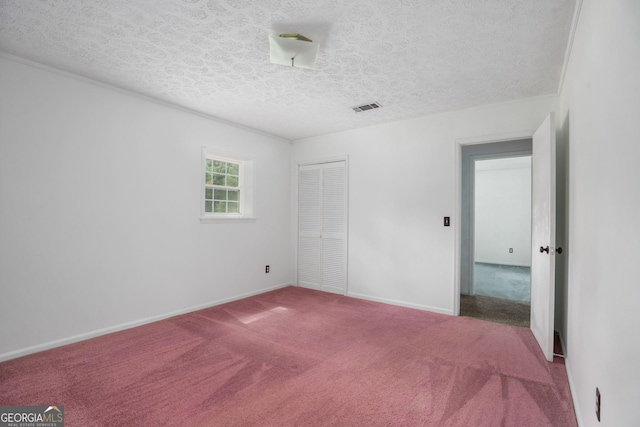 unfurnished bedroom with visible vents, a textured ceiling, a closet, and carpet