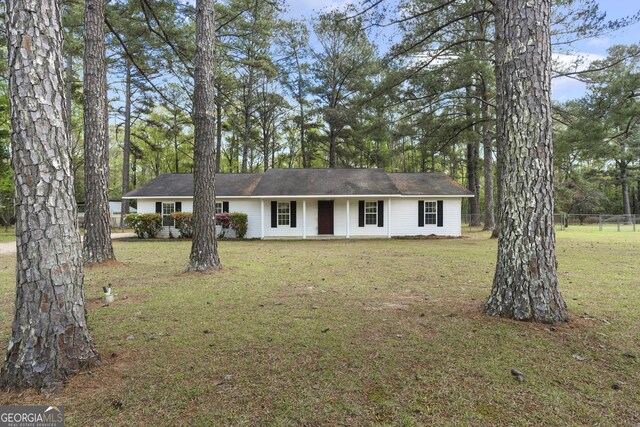 ranch-style home featuring a front yard, covered porch, and fence