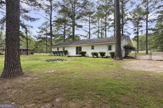 exterior space with a gate, fence, and a lawn