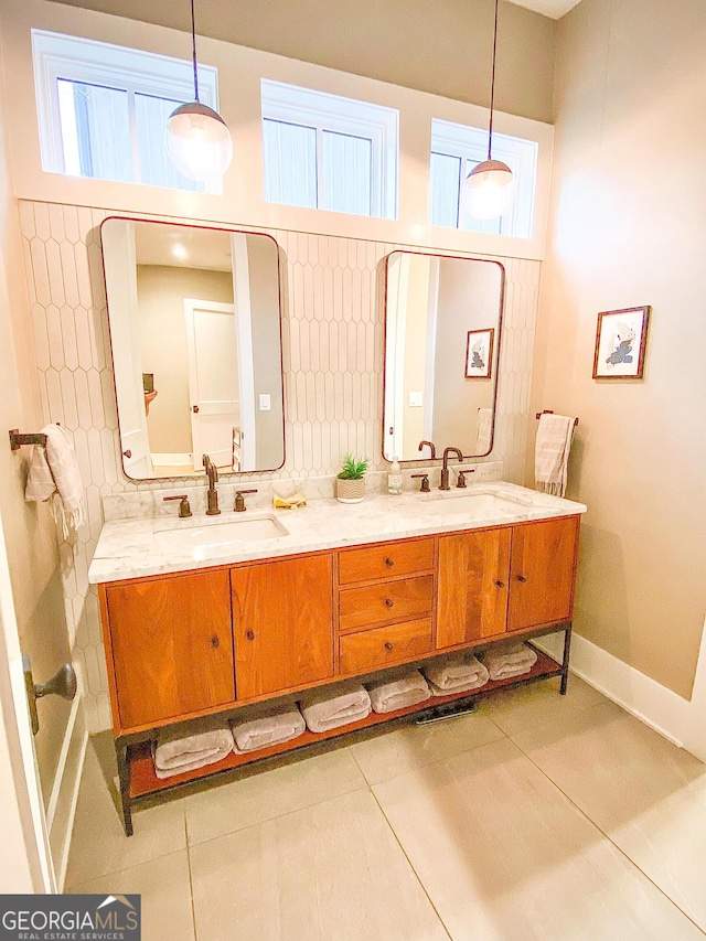 full bath with tile patterned floors, double vanity, a sink, and baseboards