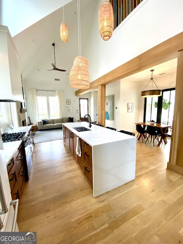 kitchen with a sink, light countertops, light wood-style flooring, and a towering ceiling