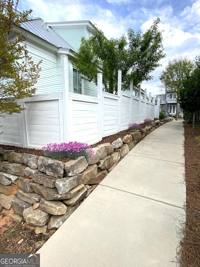view of side of property featuring metal roof and fence