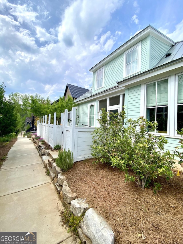 view of home's exterior featuring fence and metal roof