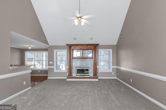 unfurnished living room featuring carpet, ceiling fan, a glass covered fireplace, and baseboards
