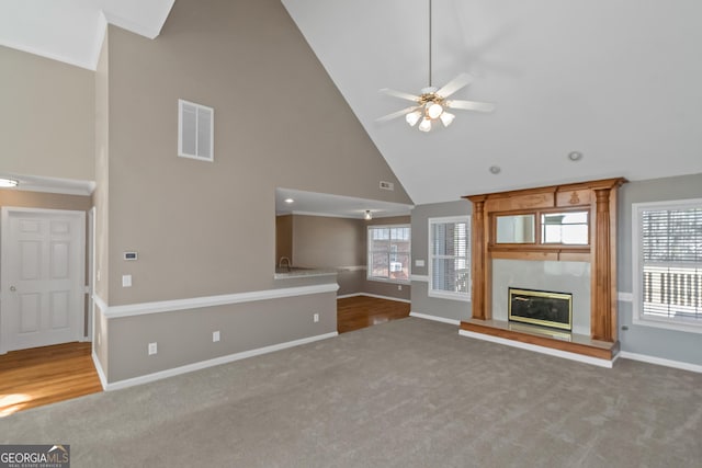 unfurnished living room with carpet floors, plenty of natural light, baseboards, visible vents, and high vaulted ceiling