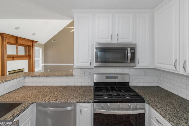 kitchen featuring dark stone countertops, white cabinetry, stainless steel appliances, and decorative backsplash