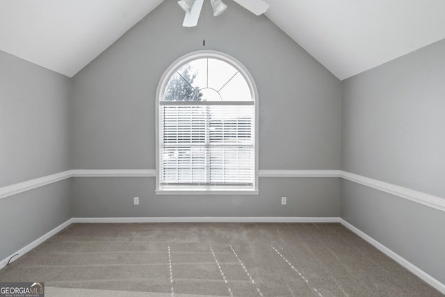 carpeted spare room featuring lofted ceiling, ceiling fan, and baseboards