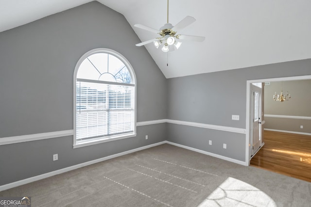 empty room featuring carpet flooring, baseboards, ceiling fan with notable chandelier, and lofted ceiling