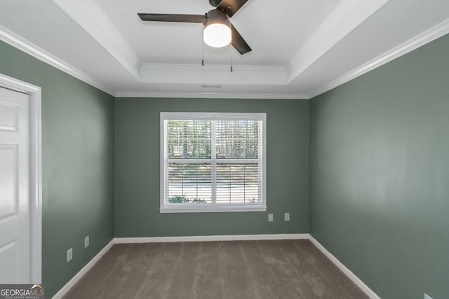 empty room featuring baseboards, a ceiling fan, dark carpet, and a tray ceiling