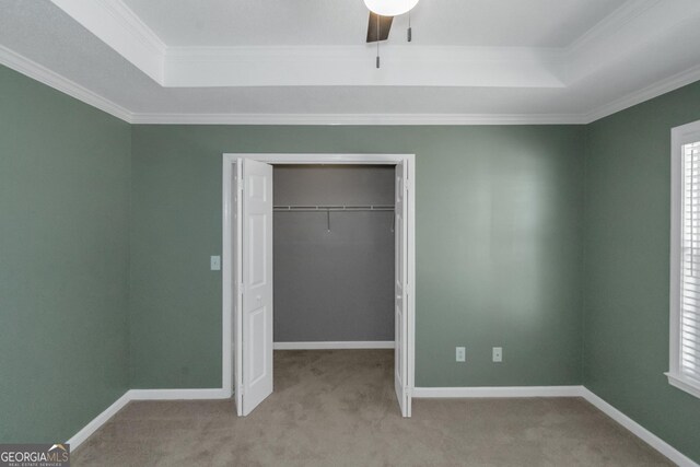 unfurnished bedroom with ornamental molding, a closet, carpet flooring, and a tray ceiling