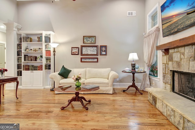 53 Gordon Manor Ct, Senoia, GA 30276 - living room featuring a high ceiling, wood finished floors, a fireplace, and decorative columns