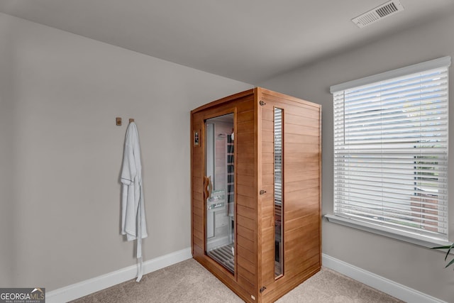 interior space with a sauna, baseboards, visible vents, and light carpet