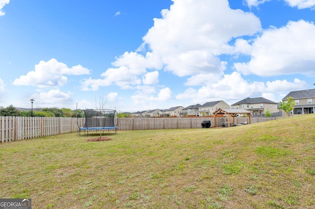 view of yard with a residential view, a trampoline, and a fenced backyard