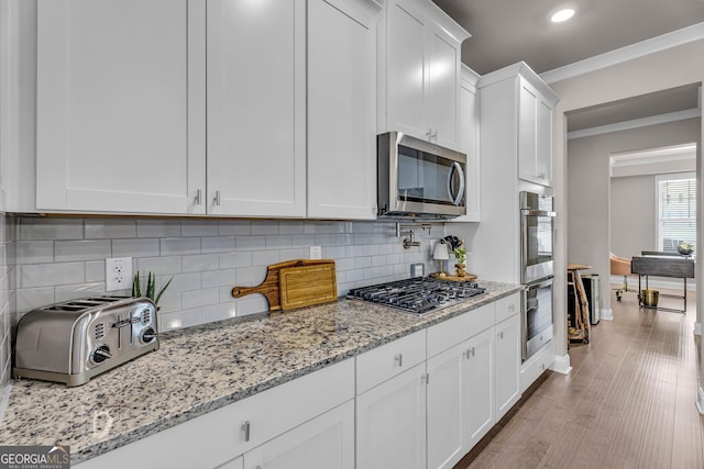 kitchen with white cabinets, crown molding, appliances with stainless steel finishes, and decorative backsplash