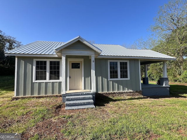 bungalow featuring metal roof, board and batten siding, and a front yard