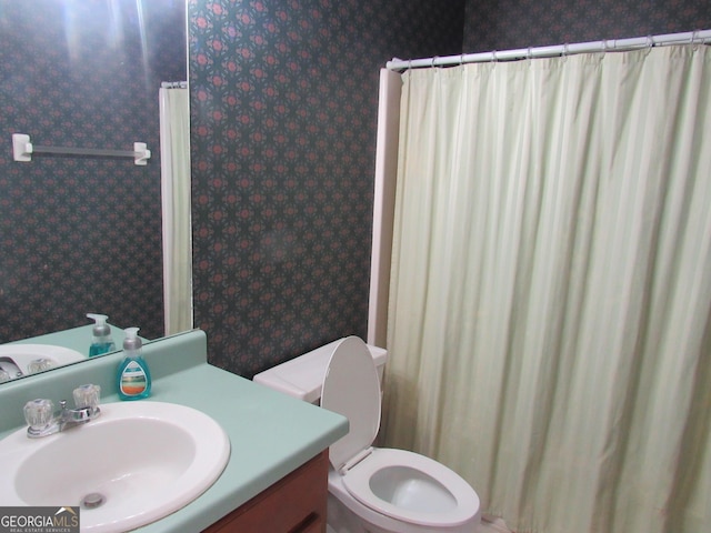 bathroom featuring wallpapered walls, toilet, vanity, and curtained shower