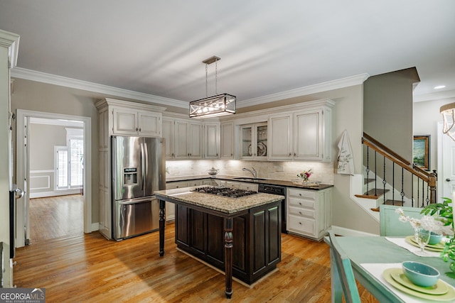 kitchen with crown molding, a sink, appliances with stainless steel finishes, hanging light fixtures, and backsplash