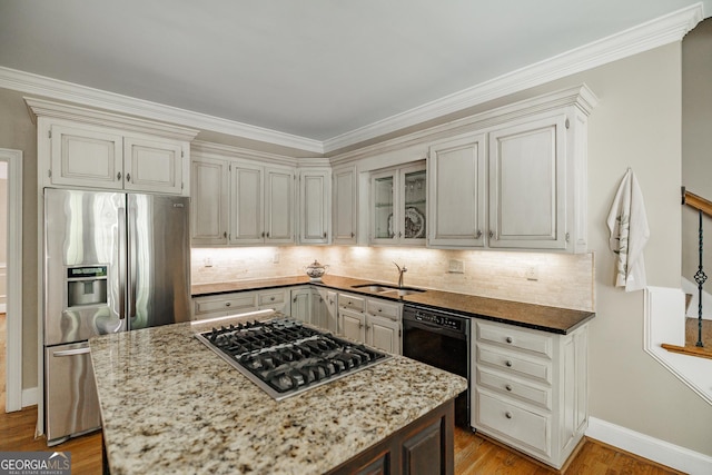 kitchen featuring tasteful backsplash, a sink, stainless steel appliances, light wood-type flooring, and light stone countertops