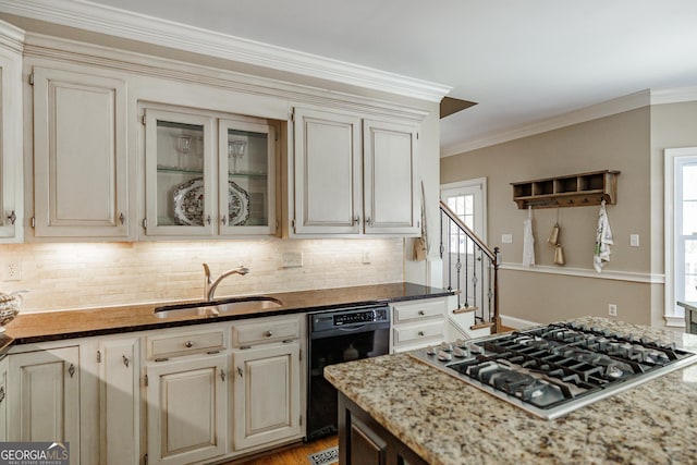 kitchen with dark stone countertops, stainless steel gas cooktop, dishwasher, and a sink
