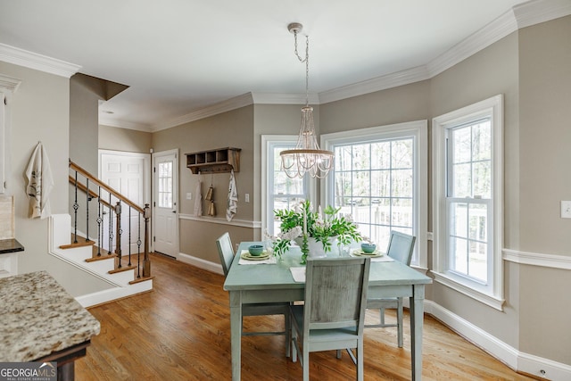 dining area featuring an inviting chandelier, stairs, light wood-style flooring, ornamental molding, and baseboards