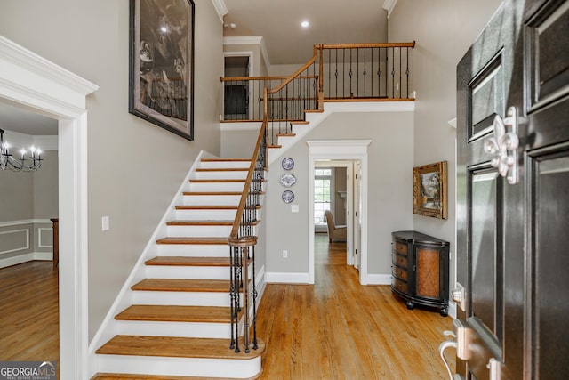 staircase with wood finished floors and crown molding